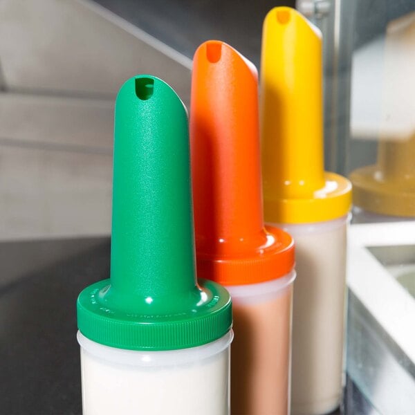 A group of Carlisle Store 'N Pour containers with different colored spouts and necks.