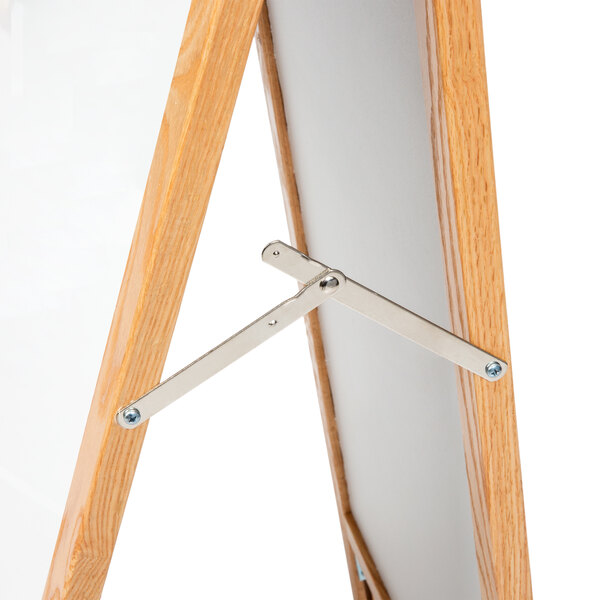An Aarco oak A-frame sign board with a white marker board on it.