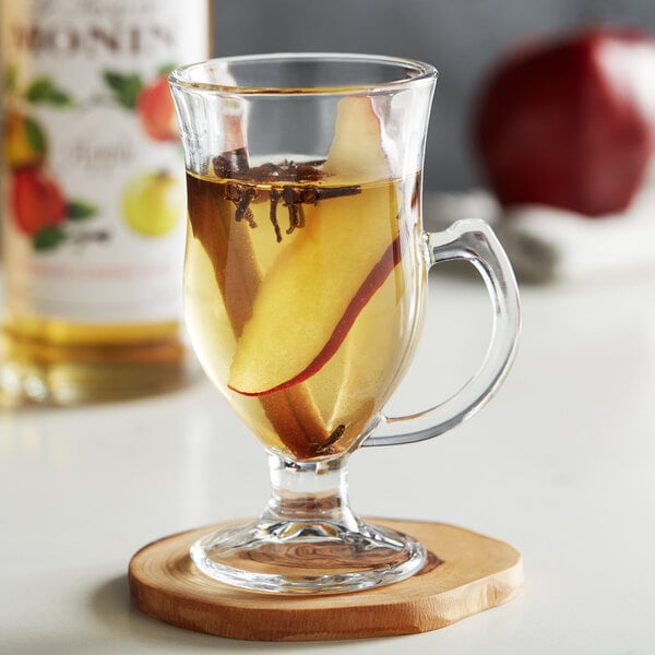 A glass of Monin apple flavored drink with fruit in it.