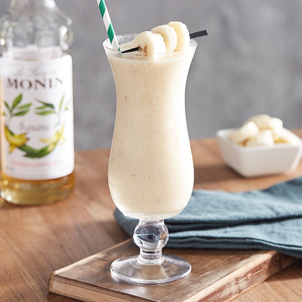 A glass of white liquid with a green and white striped straw.