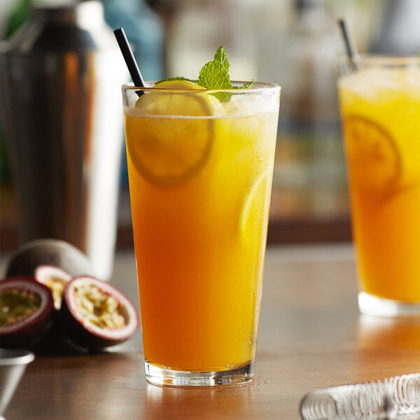 A glass of passion fruit puree with lemons and mint leaves.