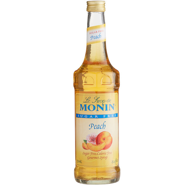 A Monin bottle of peach syrup on a table.