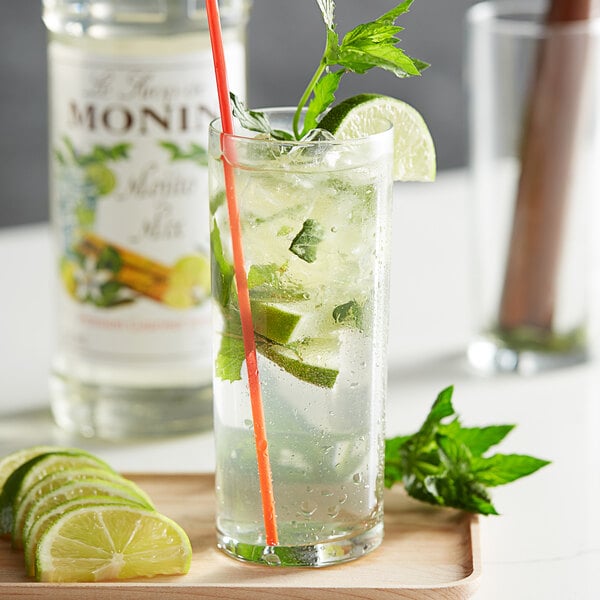 Mojito in a tall glass, garnished with lime and herbs