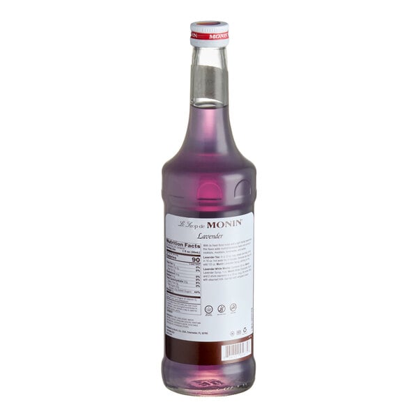 A 750 mL bottle of Monin Premium Lavender Flavoring Syrup with a purple liquid and a labeled back.