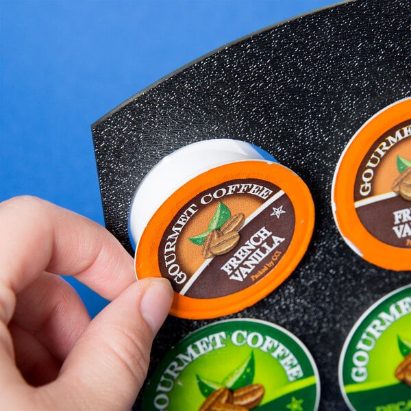 A hand holding a round orange and green label.