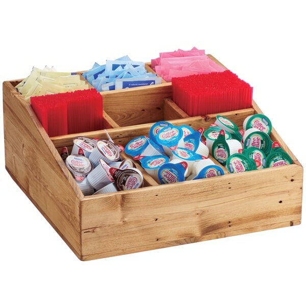 A Cal-Mil Madera rustic pine condiment organizer with 9 compartments on a wooden counter filled with various tea and coffee condiments.