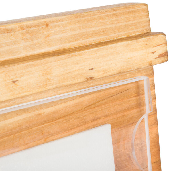 A close-up of a wooden surface with a wood frame and clear plastic displayette inside.
