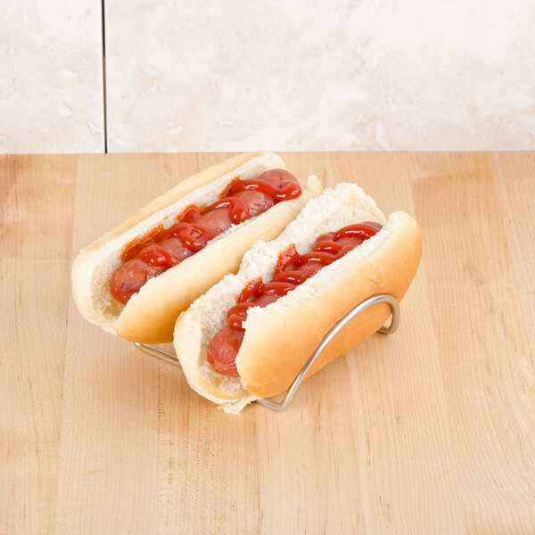 A Cal-Mil stainless steel mini taco holder holding two hot dogs with ketchup on them.