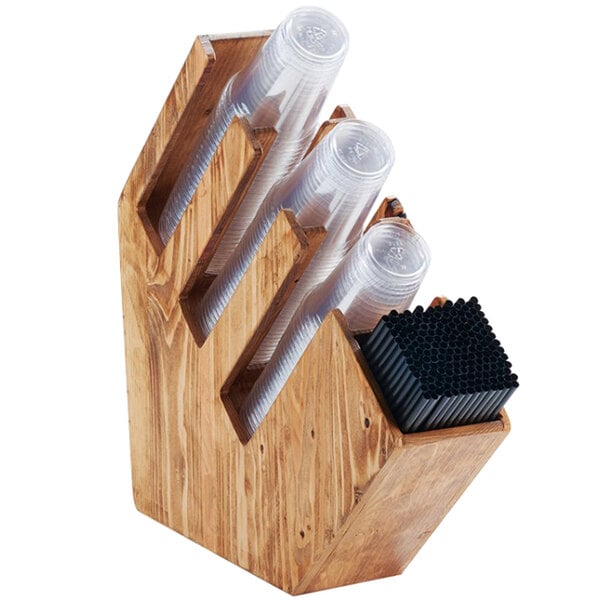 A wooden countertop organizer with three slanted sections for cups or lids and a compartment for straws.