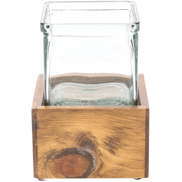 A square glass container in a wooden box.