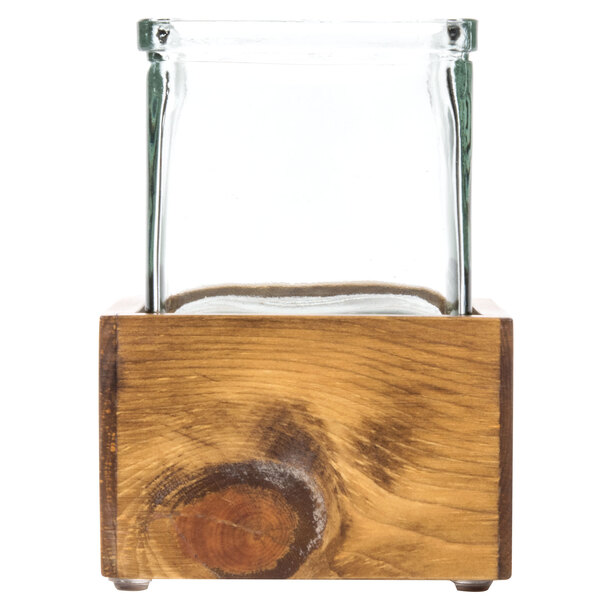 A glass jar in a wooden box with a wood grain.