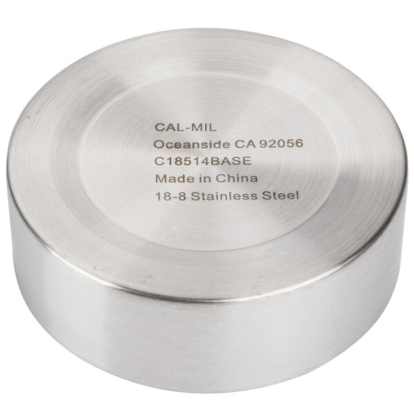 A stainless steel round metal container with a label that says "Cal-Mil" on a table.