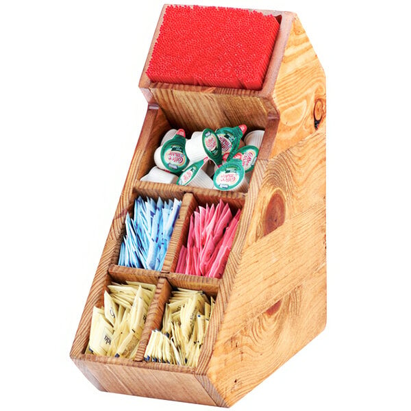 A Cal-Mil Madera wooden box with removable dividers holding coffee condiments and stir sticks.