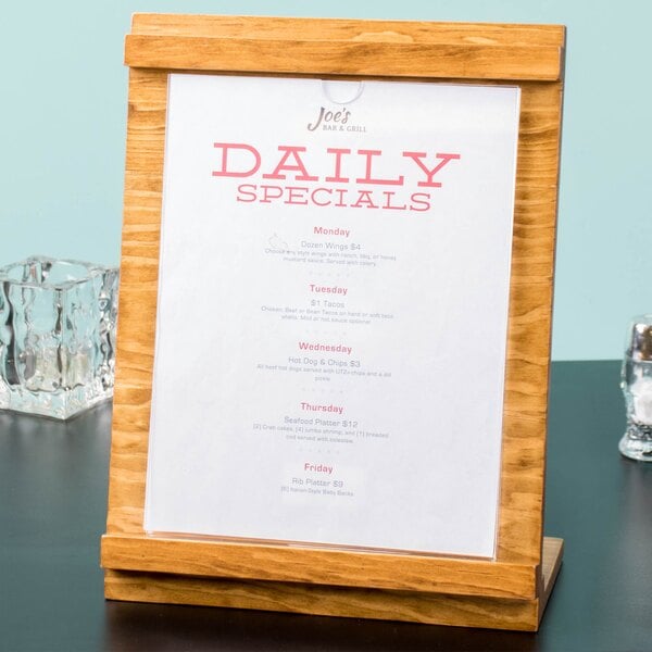 A wooden table with a Cal-Mil Madera wood displayette holding a menu