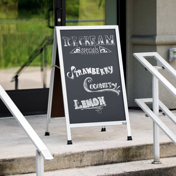 An Aarco black chalkboard A-Frame sign on a sidewalk.