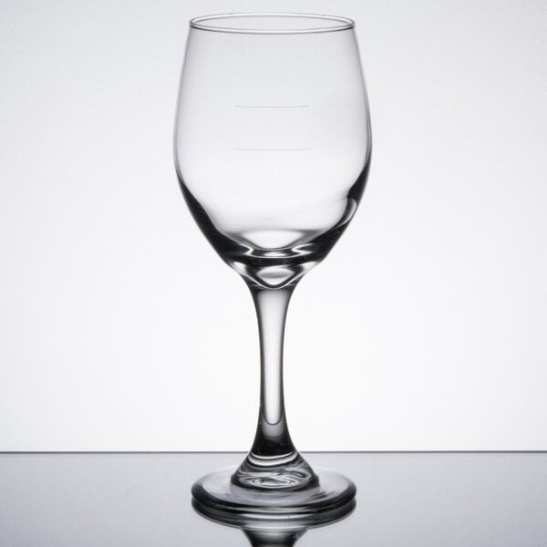 A close-up of a Libbey Perception wine goblet with pour lines on a reflective surface.