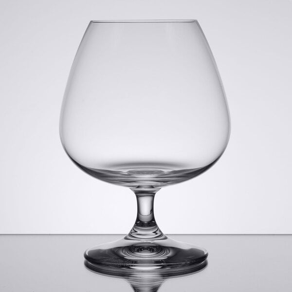 A Spiegelau Soiree cognac glass on a table with clear liquid inside.