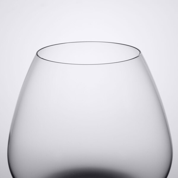 A close up of a clear Spiegelau Cognac glass with a black rim.