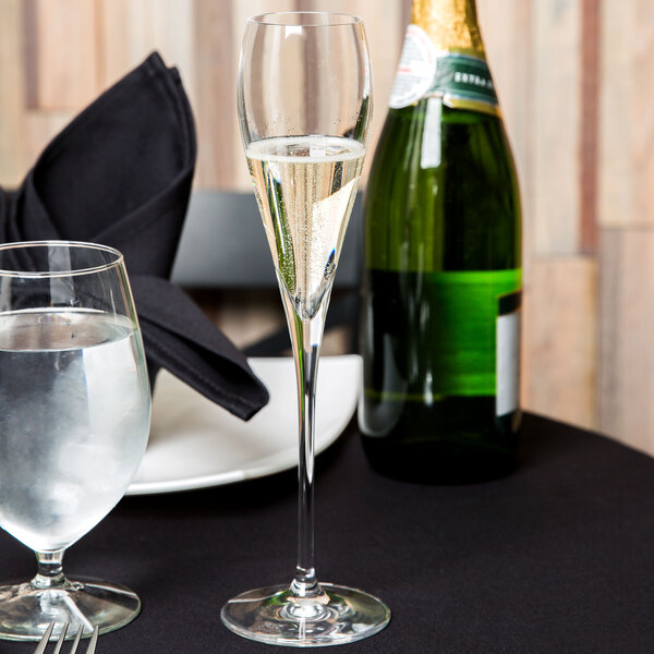 A table with a Spiegelau Adina Prestige flute of champagne and a glass of water next to a napkin.