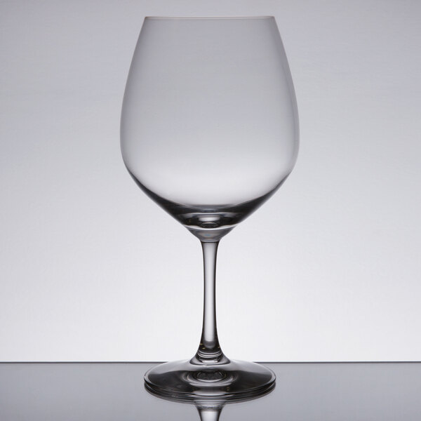 A close-up of a clear Spiegelau Vino Grande wine glass on a reflective surface.