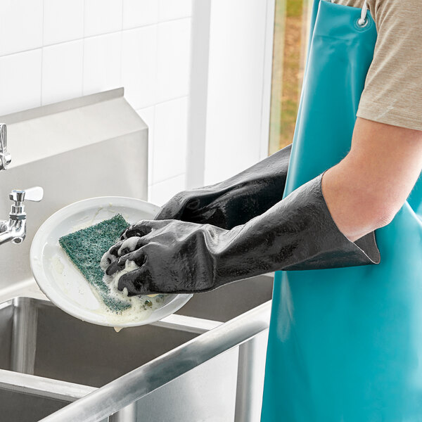 A pair of black PVC gloves with cotton lining being worn while washing dishes.