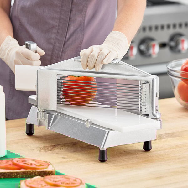 A commercial-grade tomato slicer with a metal frame and multiple blades for evenly slicing tomatoes.