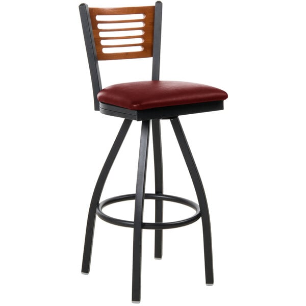 A BFM Seating black metal restaurant bar stool with a cherry wood back and burgundy vinyl seat.