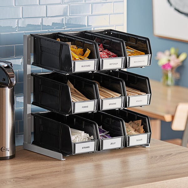 A Carlisle aluminum packet rack with black bins holding condiment packets.