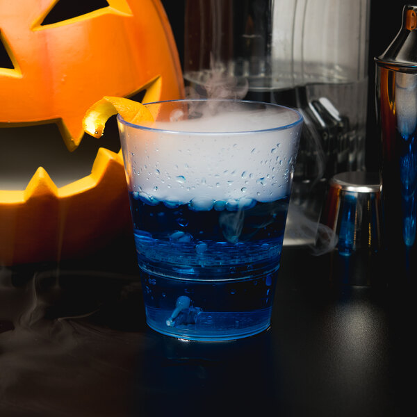 A close up of a WNA Comet clear plastic rocks glass with blue and white liquid inside.
