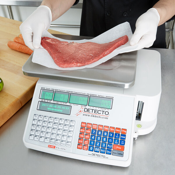 A person weighing meat on a Cardinal Detecto legal for trade scale.