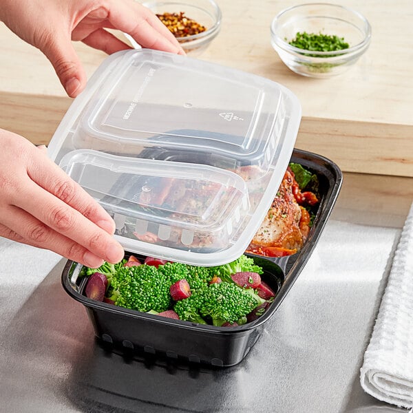 A person holding a Choice black rectangular plastic container with food inside.