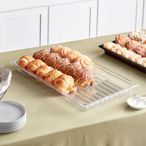 A clear Cambro market tray on a table with pastries.