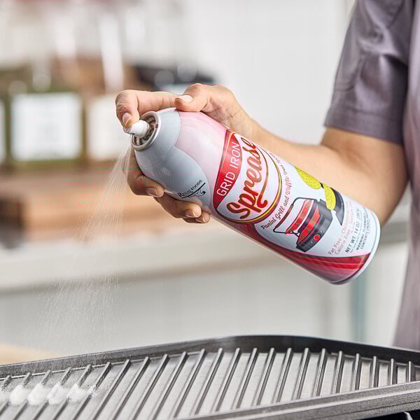A person spraying Grid Iron Sprease panini grill and waffle iron release spray onto a grill pan.