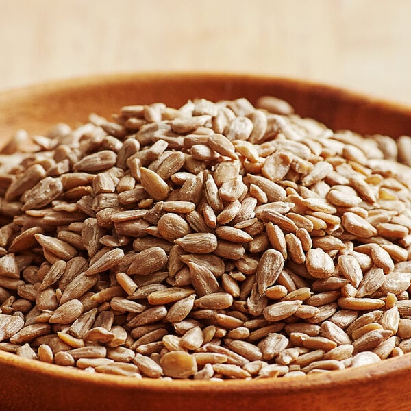 A wooden bowl of raw sunflower seeds.