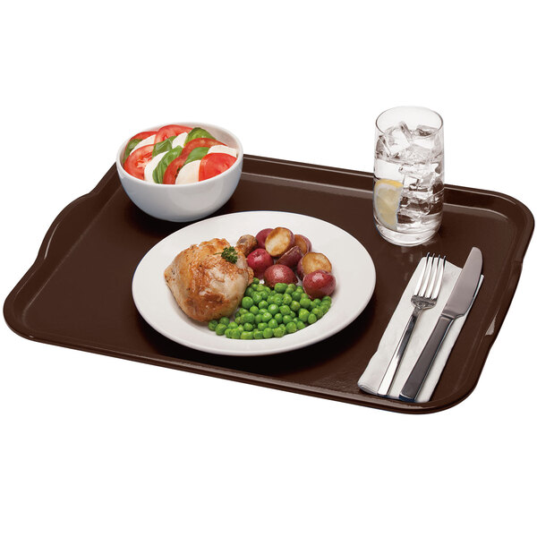 A brown rectangular Cambro tray with food on it, a fork, and a glass of water with ice and a lemon slice.