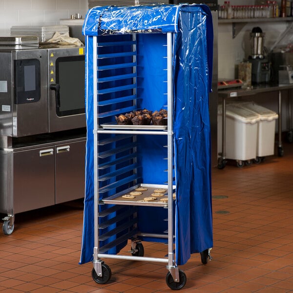 A blue vinyl bun pan rack cover fitted over a tall metal rack in a commercial kitchen.