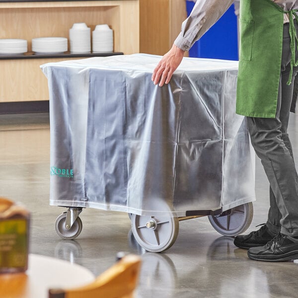 A person pushing a cart covered in translucent vinyl.