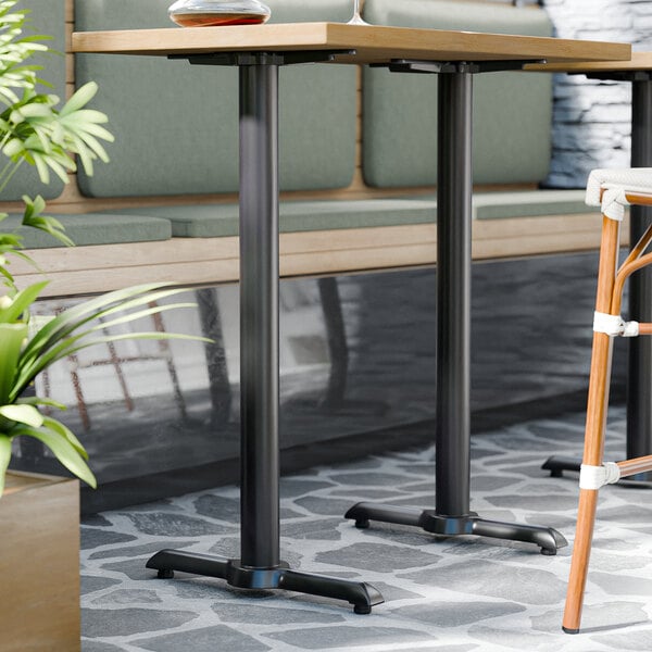 A FLAT Tech bar height table base with two chairs and a plant on it.