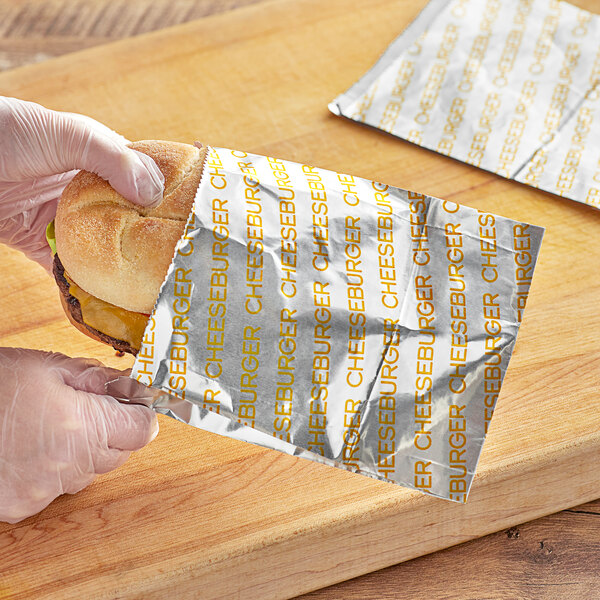 A hand placing a cheeseburger in a Carnival King paper bag.