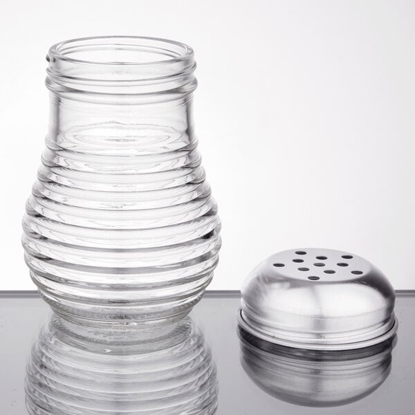 An American Metalcraft glass beehive cheese and pepper shaker with a chrome-plated lid on a table.
