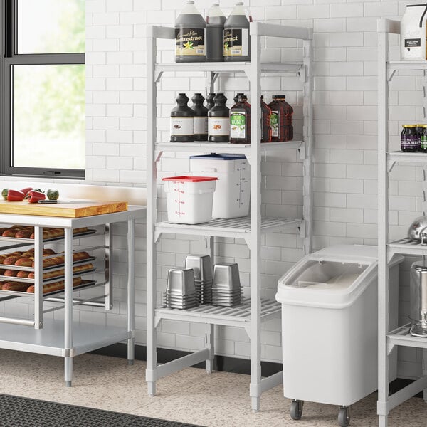 A white Cambro Camshelving unit with 4 vented shelves holding containers.