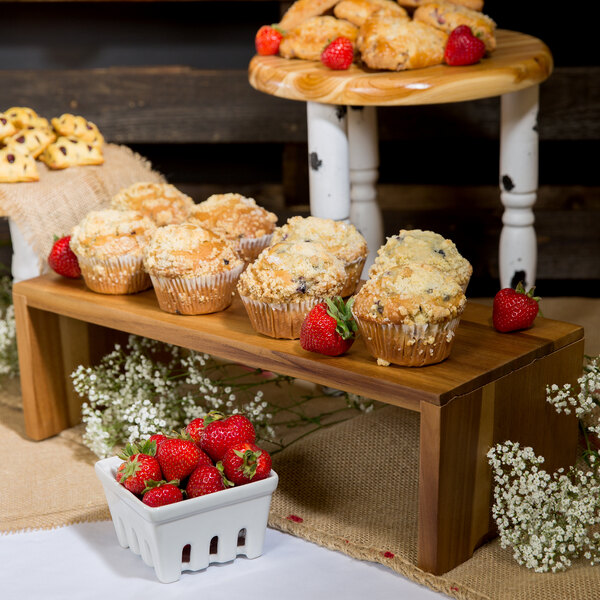 A Tablecraft Acacia Wood 3-piece Cascade Riser set holding a tray of muffins and strawberries on a table.