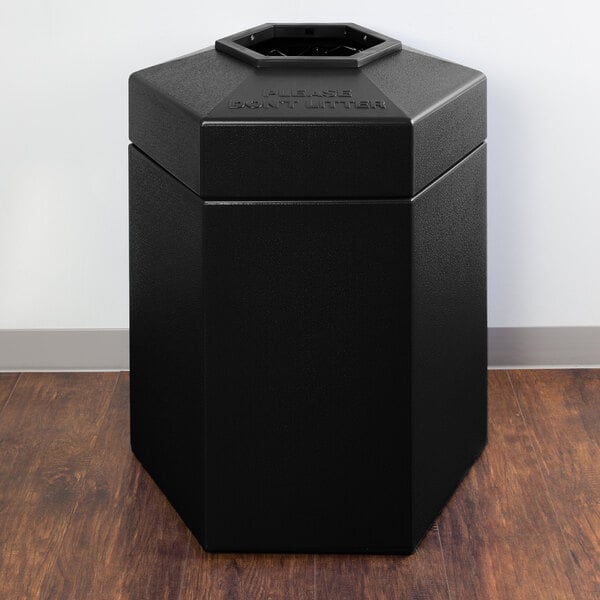 A black hexagonal Commercial Zone PolyTec trash can on a wood surface.