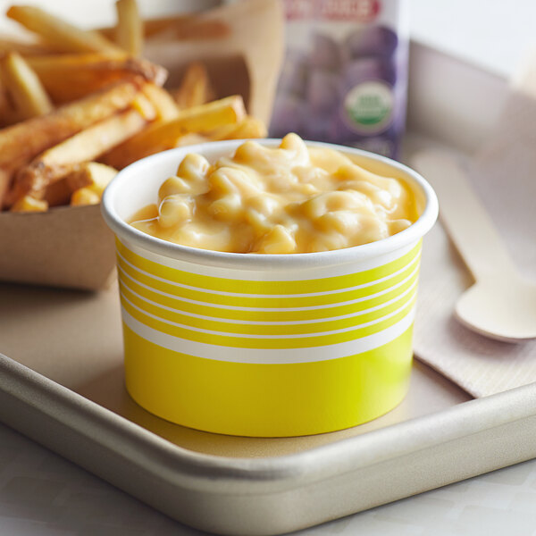 A yellow Choice paper cup filled with macaroni and cheese on a tray.