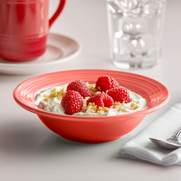 A Tuxton Cinnebar grapefruit bowl filled with fruit and nuts on a table.