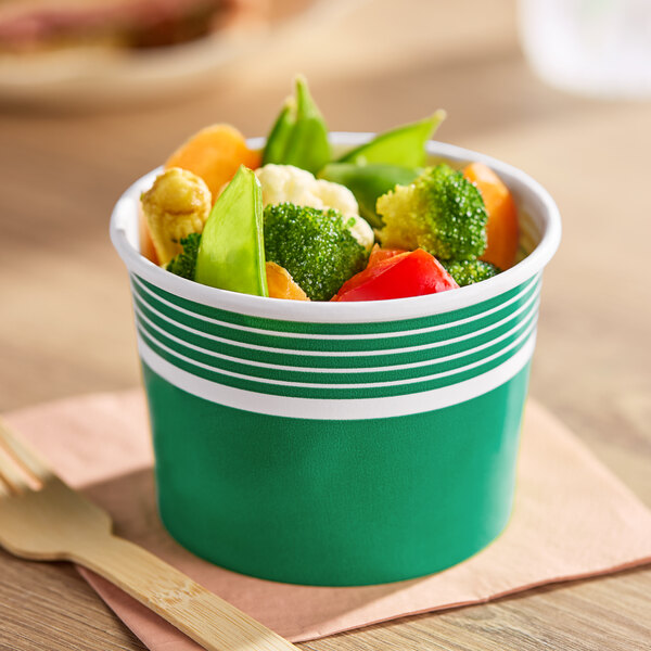 A green paper food cup filled with assorted vegetables.