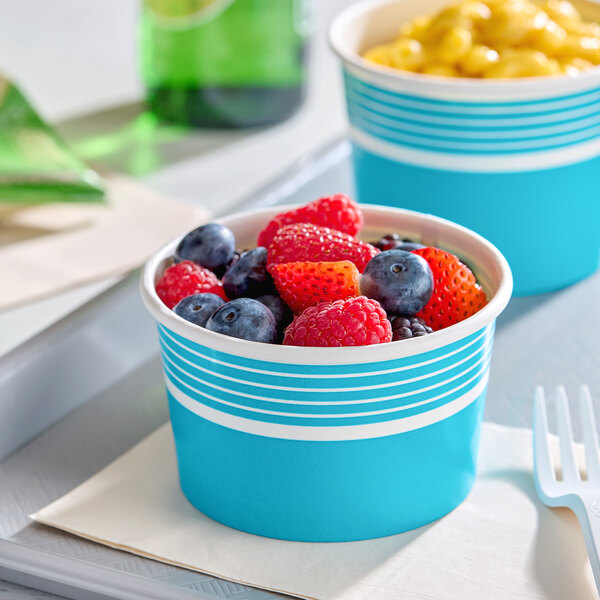 An 8 oz. blue paper food cup filled with assorted fresh berries.