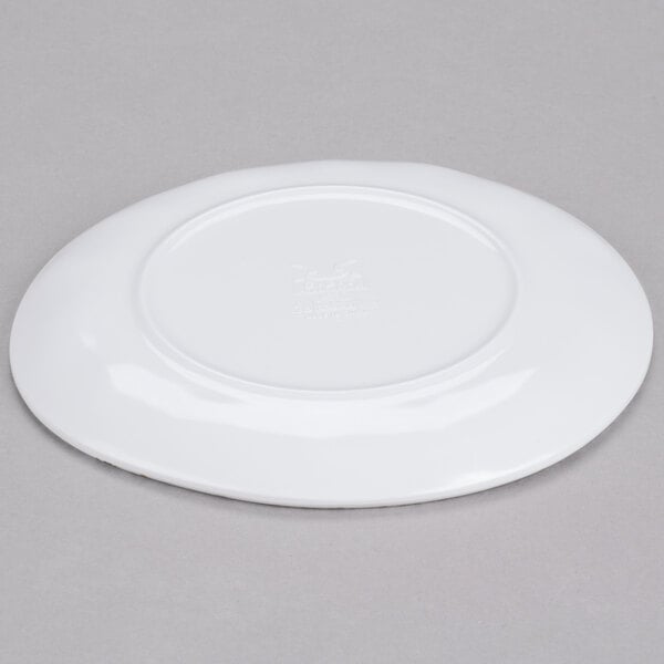 A white Urban Mill round coupe plate with an irregular shape on a gray surface.