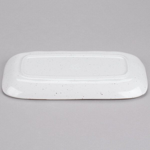 A white rectangular platter with speckled black specks.