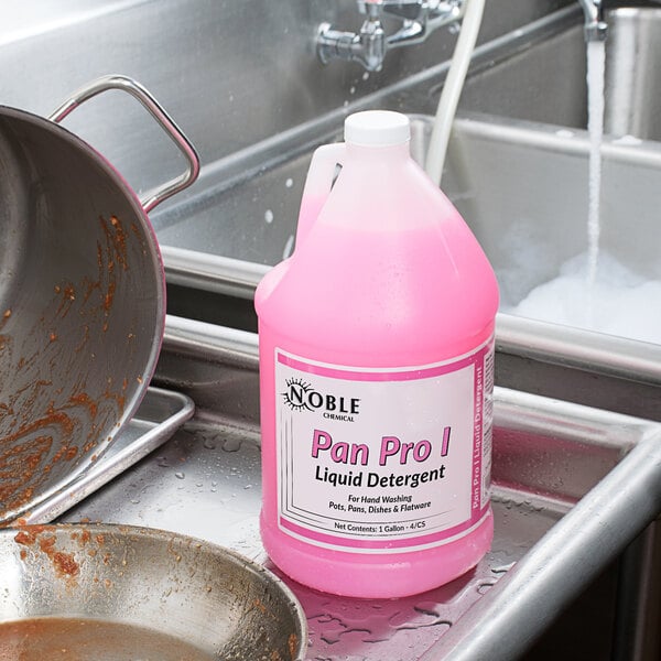 A plastic container of pink Noble Chemical Pan Pro I liquid detergent on a professional kitchen counter.